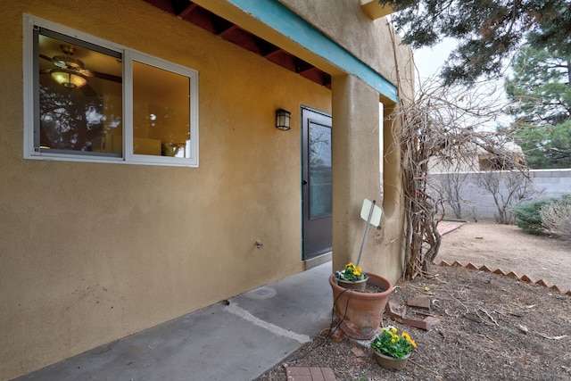 view of exterior entry with fence and stucco siding