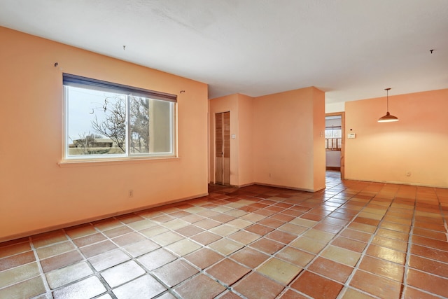 unfurnished room featuring plenty of natural light, light tile patterned flooring, and baseboards