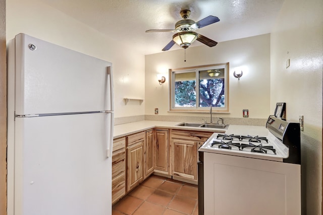 kitchen featuring white appliances, light countertops, light brown cabinetry, a sink, and light tile patterned flooring