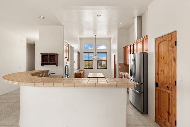 kitchen featuring light tile patterned floors, appliances with stainless steel finishes, backsplash, tile counters, and pendant lighting