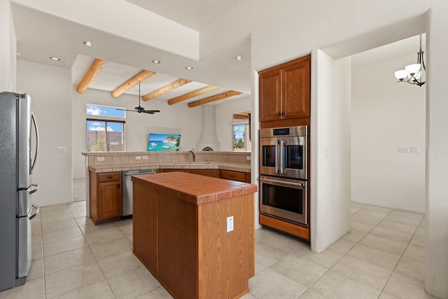 kitchen with a center island, brown cabinets, tile countertops, stainless steel appliances, and a peninsula