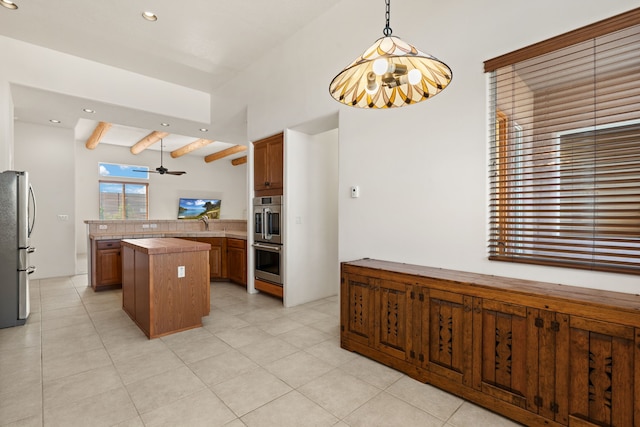 kitchen featuring stainless steel appliances, brown cabinetry, a kitchen island, and beam ceiling