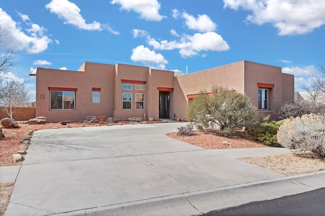 pueblo-style home featuring concrete driveway and stucco siding