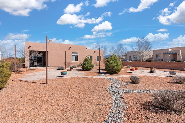 back of house featuring a patio, an outdoor fire pit, fence, and stucco siding