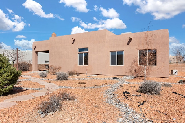 rear view of property with fence and stucco siding