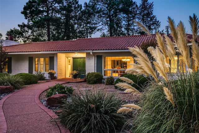 mediterranean / spanish-style house with brick siding and a tiled roof