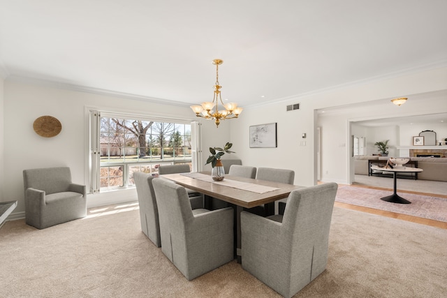 dining area with baseboards, visible vents, light colored carpet, ornamental molding, and a notable chandelier