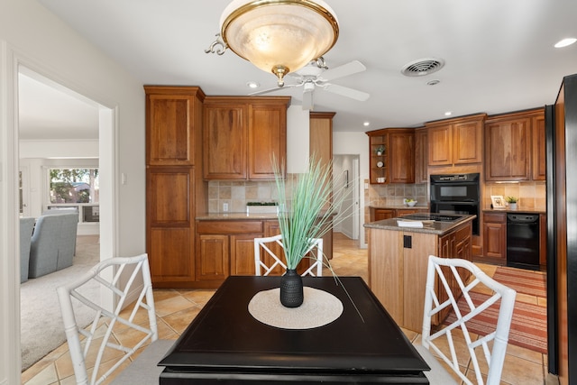 kitchen with visible vents, brown cabinetry, backsplash, and a center island