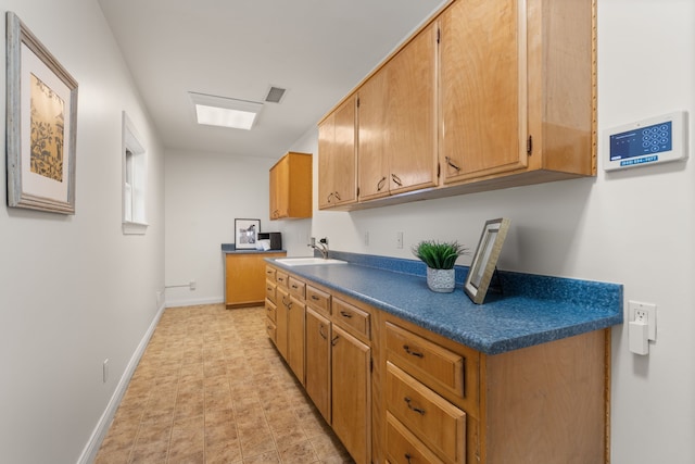 kitchen featuring dark countertops, visible vents, a sink, and baseboards