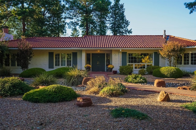 ranch-style house featuring a tile roof and brick siding