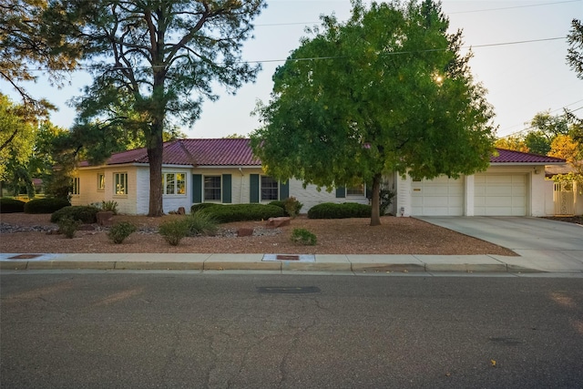 view of front of house featuring a tile roof, driveway, and an attached garage