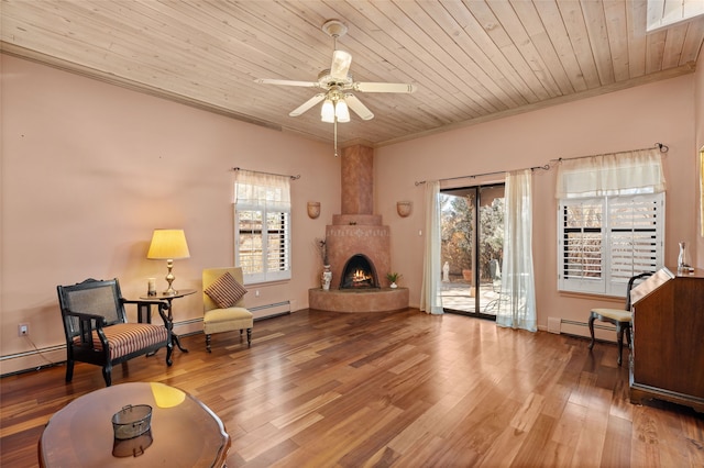 sitting room with a baseboard heating unit, wood finished floors, wood ceiling, and crown molding