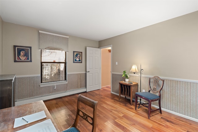 living area featuring wainscoting, baseboard heating, and wood finished floors