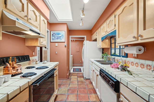 kitchen featuring under cabinet range hood, white appliances, a skylight, a sink, and tile counters