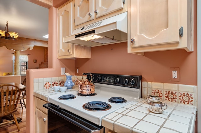 kitchen featuring tile counters, range with electric stovetop, and under cabinet range hood