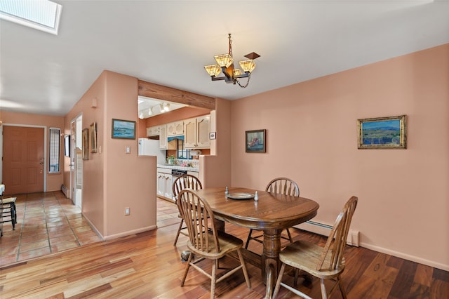 dining area featuring a skylight, visible vents, baseboards, light wood-style flooring, and a chandelier