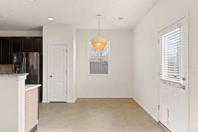 unfurnished dining area with baseboards and visible vents