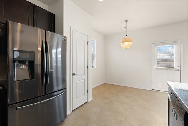 kitchen featuring baseboards, stainless steel fridge, decorative light fixtures, and a healthy amount of sunlight