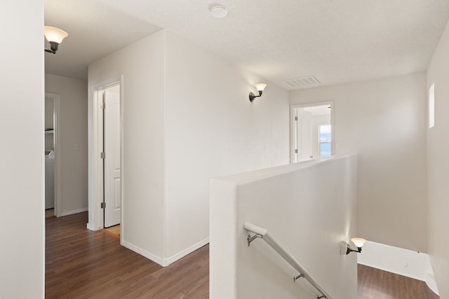 hall with baseboards, visible vents, an upstairs landing, and wood finished floors