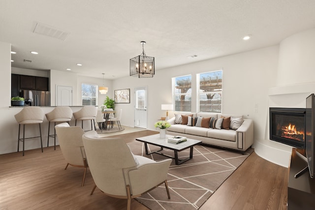 living area with plenty of natural light, visible vents, and wood finished floors