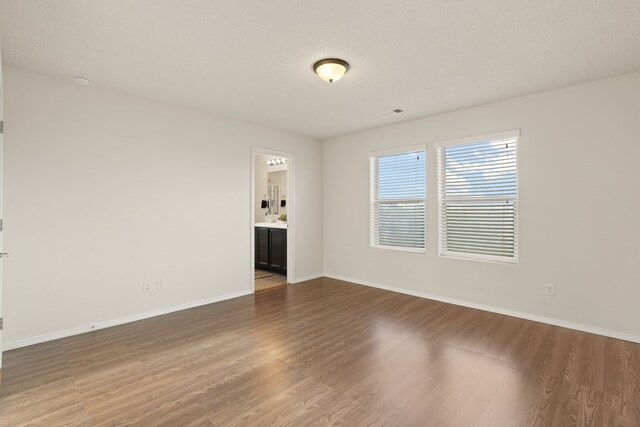 spare room with visible vents, baseboards, and wood finished floors