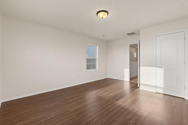 unfurnished bedroom featuring dark wood-style flooring, visible vents, and baseboards