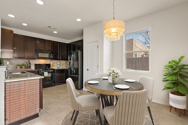 kitchen featuring a sink, visible vents, dark brown cabinets, backsplash, and black appliances