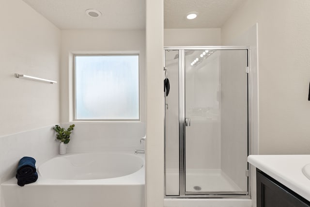 bathroom with a stall shower, a textured ceiling, vanity, and a bath