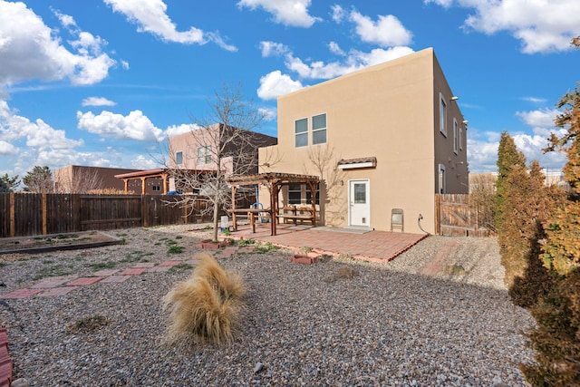 back of house featuring stucco siding, a patio area, a fenced backyard, and a pergola