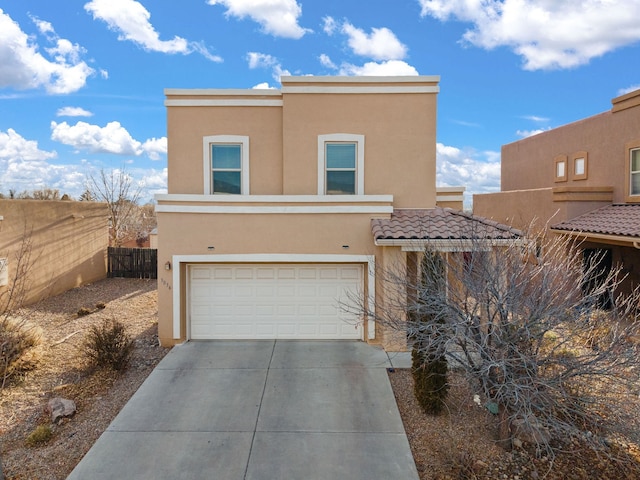 view of front of property featuring driveway, an attached garage, fence, and stucco siding