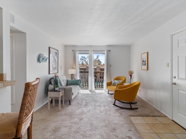 living area featuring baseboards, light carpet, and a textured ceiling