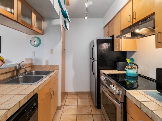 kitchen featuring under cabinet range hood, tile countertops, appliances with stainless steel finishes, and a sink