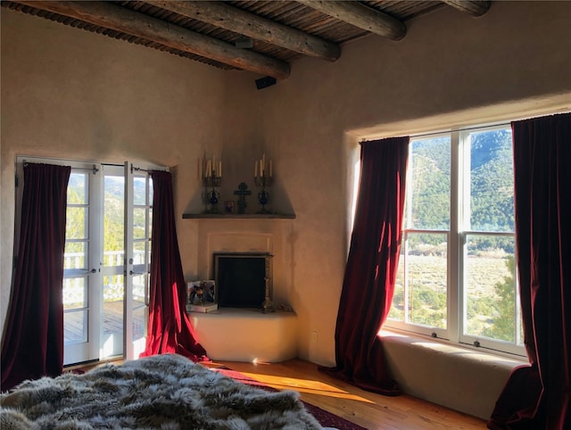 bedroom featuring wooden ceiling, a fireplace, beam ceiling, and wood finished floors