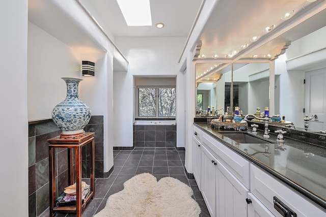 bathroom with a skylight, wainscoting, tile patterned flooring, vanity, and tile walls