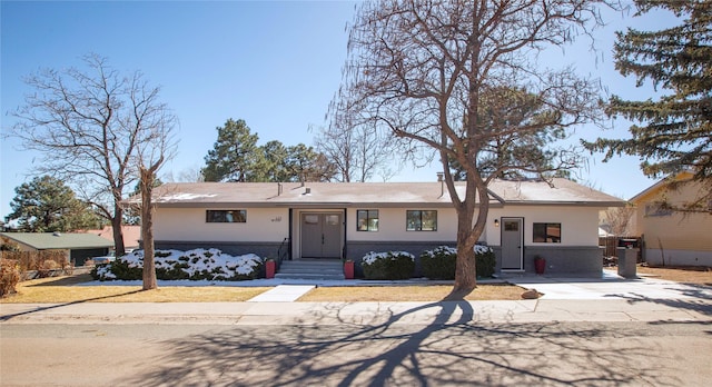 view of front facade with entry steps, brick siding, and stucco siding