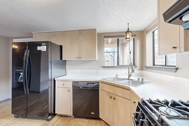 kitchen with black appliances, light brown cabinetry, a sink, and light countertops