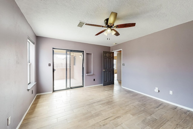 unfurnished room featuring a ceiling fan, baseboards, a textured ceiling, and light wood finished floors