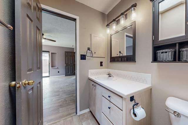 bathroom featuring toilet, ceiling fan, wood tiled floor, a textured ceiling, and vanity