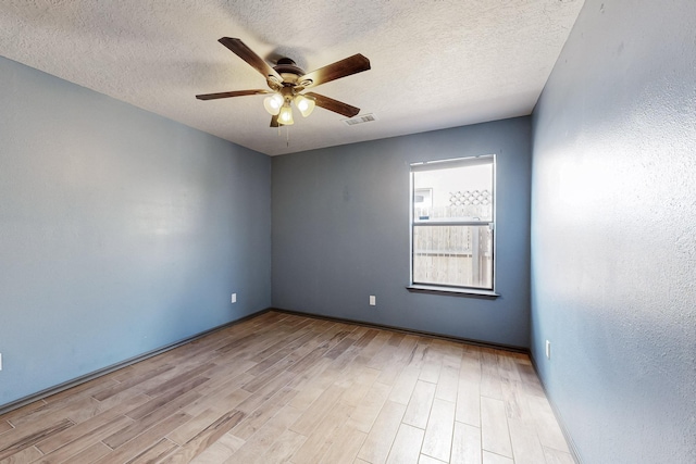 empty room with visible vents, a textured wall, a ceiling fan, a textured ceiling, and wood finished floors