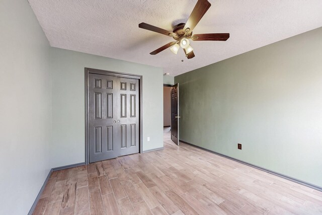 unfurnished bedroom featuring baseboards, a ceiling fan, a textured ceiling, light wood-type flooring, and a closet