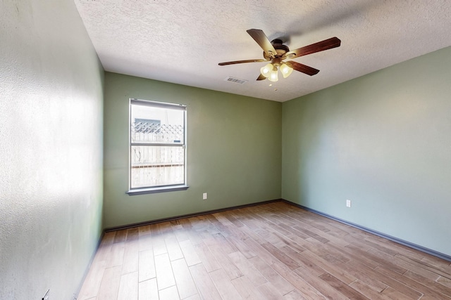 spare room with a ceiling fan, visible vents, a textured ceiling, and wood finished floors