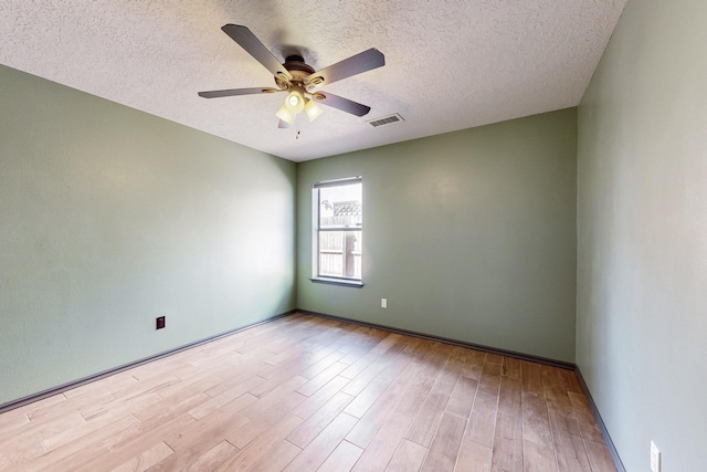 empty room with ceiling fan, a textured ceiling, wood finished floors, and visible vents