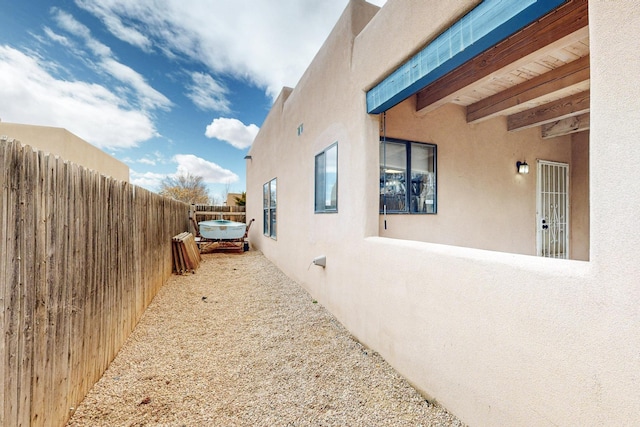 view of side of home with a fenced backyard and stucco siding