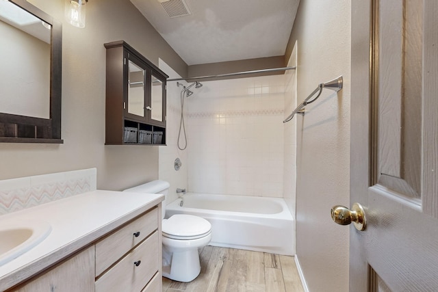 bathroom featuring shower / bath combination, visible vents, toilet, wood finished floors, and vanity