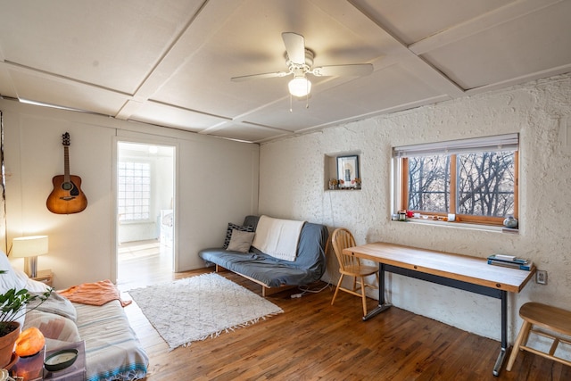 bedroom with wood-type flooring, coffered ceiling, a textured wall, and ceiling fan