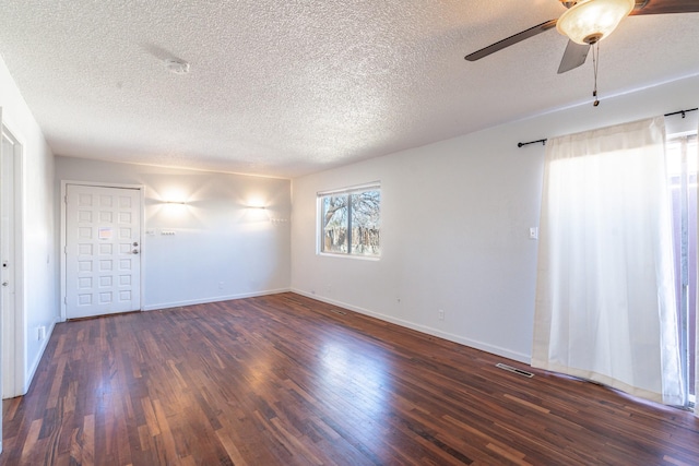 empty room with visible vents, wood finished floors, a ceiling fan, and baseboards