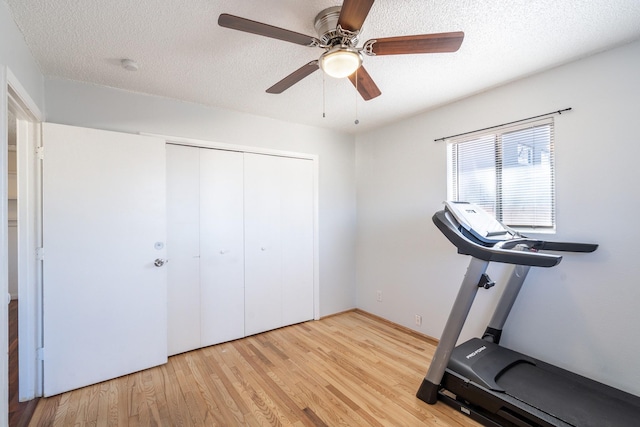 workout room with light wood-style floors, a ceiling fan, and a textured ceiling