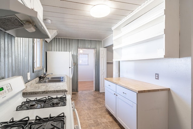 kitchen with white range with gas stovetop, white cabinets, wood counters, under cabinet range hood, and a sink