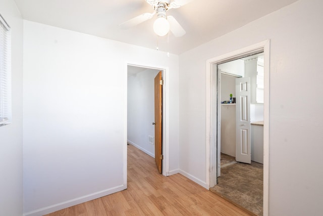 corridor with light wood-type flooring and baseboards