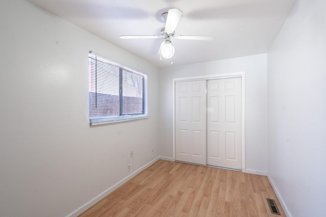 unfurnished bedroom featuring a closet, visible vents, light wood-style flooring, ceiling fan, and baseboards